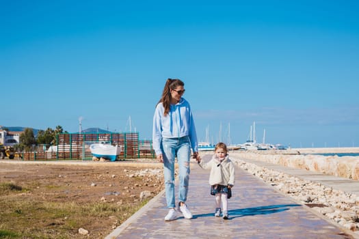 mother and little daughter walking on summer tropical beach