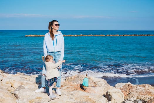 Back view of mother and her little daughter looking at the sea