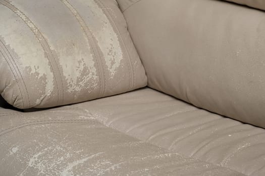 Defects on a white leather sofa. Damaged to leather furniture. Close up of damaged white leather soft tufted furniture. Bad quality leather