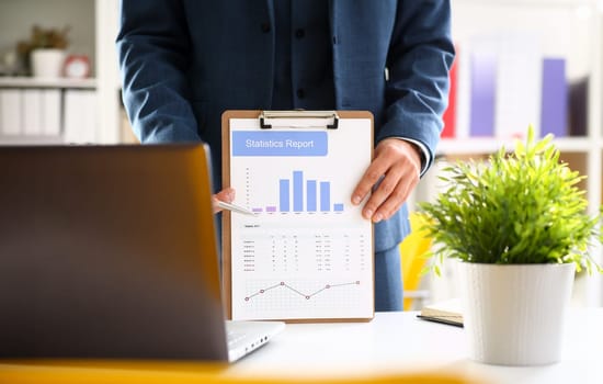 Male arm in suit show stats graphic clipped to pad in office closeup. Stock exchange market advisor participation in negotiation study trade process white collar inspector check or explain money data