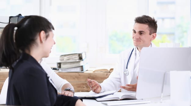 Male family doctor listen carefully young couple in office portrait. Motherhood and child delivery new life or abortion therapeutist reception service physical hospital and clinic concept