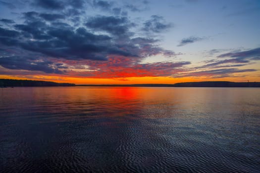 Scenic red sunset sky reflecting in the lake or river surface. High quality photo