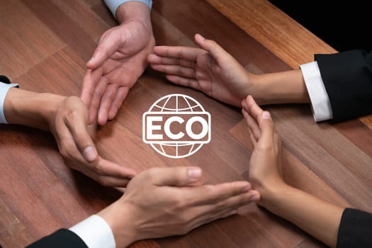 Top view group of business people forming circle hand together around ECO icon on meeting table as concept of corporate responsible for eco-friendly investment for greener community. Quaint