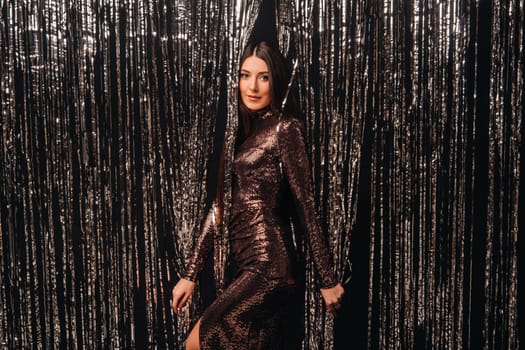 girl in a shiny dress on a silver background of New Year's rain.