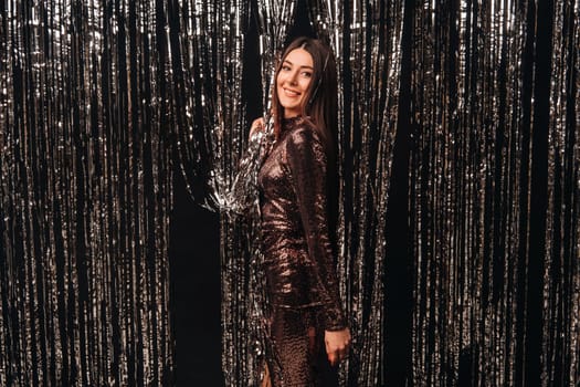 girl in a shiny dress on a silver background of New Year's rain.