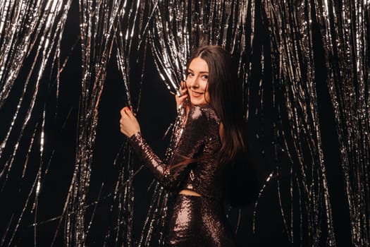 girl in a shiny dress on a silver background of New Year's rain.