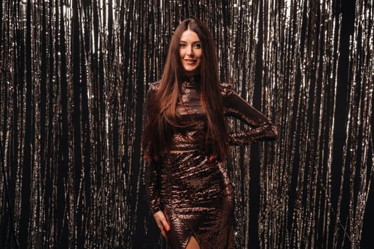 girl in a shiny dress on a silver background of New Year's rain.