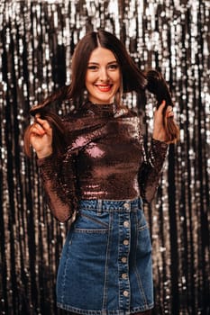 a girl in a shiny jacket on a silver background of New Year's rain.