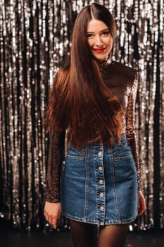 a girl in a shiny jacket on a silver background of New Year's rain.