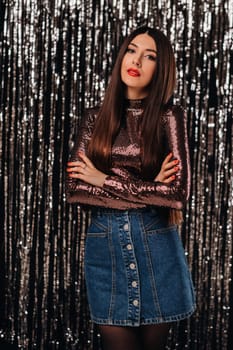 a girl in a shiny jacket on a silver background of New Year's rain.