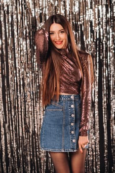 a girl in a shiny jacket on a silver background of New Year's rain.