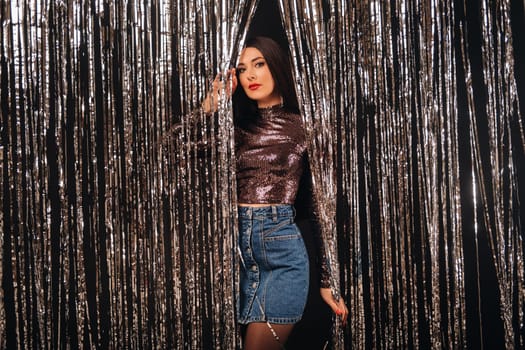 a girl in a shiny jacket on a silver background of New Year's rain.