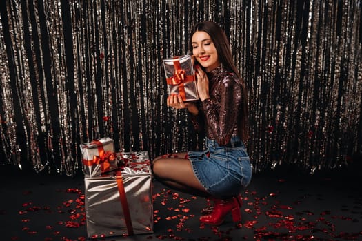 a girl in a shiny jacket and skirt with gifts on a silver background in the form of rain.