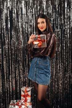 a girl in a shiny jacket and skirt with gifts on a silver background in the form of rain.