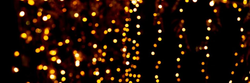 Blurry garland lights on a dark background. Festive Christmas and New Year background. Soft focus.