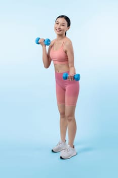 Vigorous energetic woman doing dumbbell weight lifting exercise on isolated background. Young athletic asian woman strength and endurance training session as body workout routine.