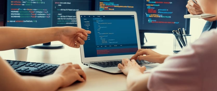 Two smart cooperative computer engineers working together as teamwork to solve program code while computer screen displayed program code. Laptop, web development, programer, java script . Burgeoning.