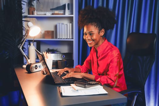 African woman blogger wearing pink shirt with happy face, looking on screen laptop with valued achievement project or get scholarship. Concept of cheerful expression work from home. Tastemaker.