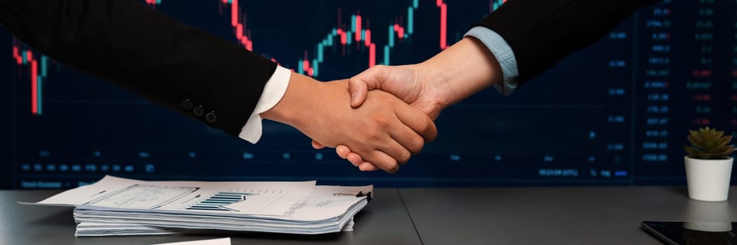 Stock investors celebrate successful profit from selling stock and shaking hand with each other, market analysis and strategic decision-making led to successful stock trading exchange. Trailblazing