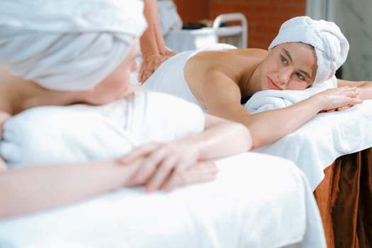 A portrait of two attractive young women with beautiful skin in white towel having a back massage by professional masseur at traditional spa salon. Beauty and healthy. Tranquility.