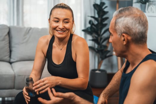 Athletic and sporty senior couple portrait in sportswear sitting on sofa as home exercise concept. Healthy fit body lifestyle after retirement. Clout