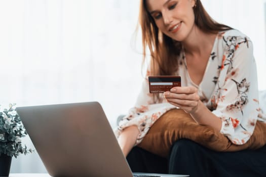 Young happy woman buy product by online shopping at home while ordering items from the internet with credit card online payment system protected by utmost cyber security from online store platform