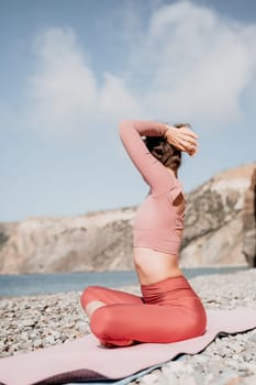 Young woman with long hair in white swimsuit and boho style braclets practicing outdoors on yoga mat by the sea on a sunset. Women's yoga fitness routine. Healthy lifestyle, harmony and meditation