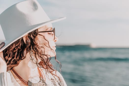 Portrait of a curly haired woman in a white hat and glasses on the background of the sea