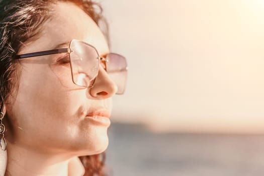 Portrait of a curly woman in glasses on the background of the sea. Vacation on the sea, walk, tourism