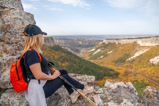 woman backpack on mountain peak looking in beautiful mountain valley in autumn. Landscape with sporty young woman, blu sky in fall. Hiking. Nature.
