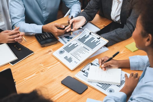 Multiracial analyst team use BI dashboard data to analyze financial report on meeting table. Group of diverse business people utilize data analysis by FIntech for business marketing decision. Concord