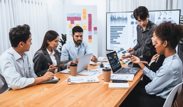 Multiracial analyst team use BI Fintech software to analyze financial data on meeting table. Financial dashboard data display on laptop screen with analyzed chart for marketing indication. Concord