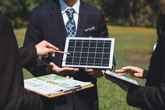 Outdoor business meeting on solar energy, group of business people working and brainstorming on alternative energy technology utilization as corporate commitment to CSR effort. Gyre