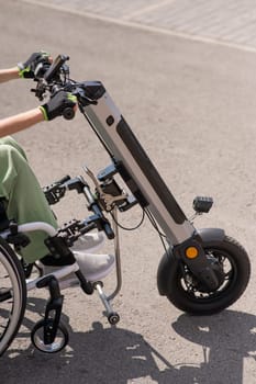 A woman controls a wheelchair using a special manual device. Close up an electric handbike