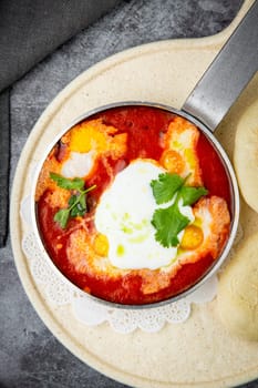 borscht in a frying pan with fresh flatbreads and cherry tomatoes