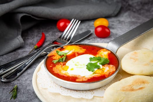 borscht in a frying pan with fresh flatbreads and cherry tomatoes