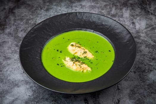 creamy broccoli soup with herbs in a black plate