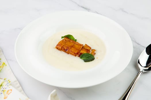 porridge with mint leaves and pieces of meat in sweet and sour sauce