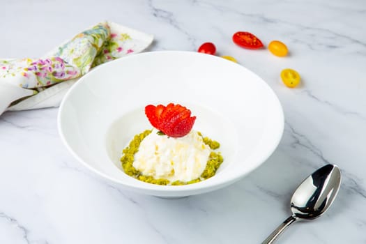 curd dessert with strawberries on top in a white plate on a marble background