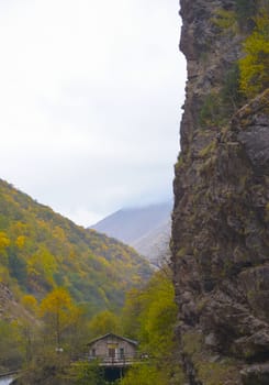 A small house near a mountain river and the foot of the misty mountains. North Caucasus, Russia