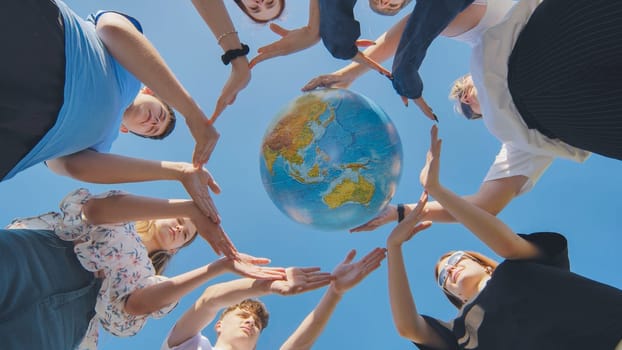 Young boys surround the globe of the world with their palms. The concept of preserving world peace