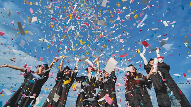 Graduates throw colorful confetti against a blue sky