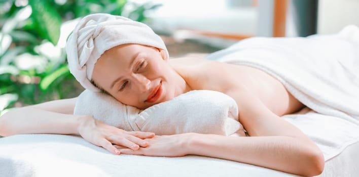 Beautiful young woman relaxes on a spa bed surrounded by nature. ready for a body massage. Attractive female in white towel lying peacefully during waiting for body massage. Close up. Tranquility