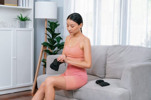 Fit young asian woman portrait in sportswear preparing herself before healthy exercising routine at home. Domestic fitness workout training on living room. Vigorous