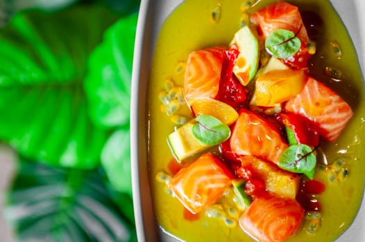 Salmon ceviche with avocado, orange and mango salsa on a light wooden background