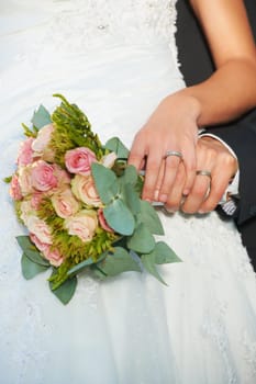 Couple, wedding ring and hands on rose bouquet in marriage with bride at celebration and event. Flower, loyalty and care with romance with love and commitment with woman and man and floral plant.