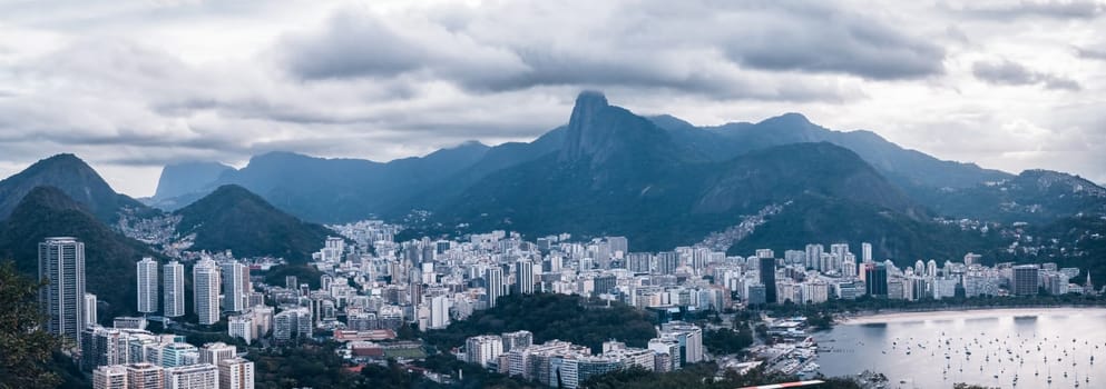 Stunning panoramic view of Rio de Janeiro from Morro de Urca, featuring a stormy, cloud-capped Christ and impressive city mountains.