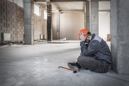 Builder man holding his head on construction site, health problems.