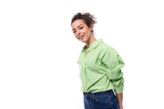 young slender european brunette curly woman with a ponytail hairstyle is dressed in a green shirt.