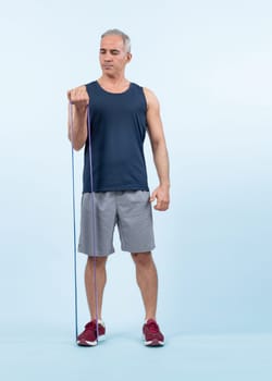 Full body length shot athletic and sporty senior man with fitness resistance band on isolated background. Healthy active physique and body care lifestyle after retirement. Clout